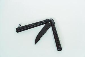 Partially open matte black balisong or butterfly knife isolated on white background. Close-up of a sharp balisong knife or butterfly knife in various positions on a white background photo