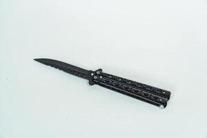 Partially open matte black balisong or butterfly knife isolated on white background. Close-up of a sharp balisong knife or butterfly knife in various positions on a white background photo