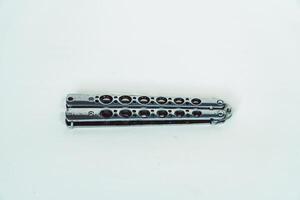 Partially open silver balisong or butterfly knife isolated on white background. Close-up of a sharp balisong knife or butterfly knife in various positions on a white background photo