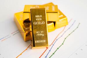 Gold bars on graph paper, finance trading investment business currency. photo