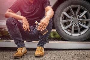 borracho hombre con whisky botella, personas Bebiendo alcohol mientras conducción un coche a choque problema a borde del camino foto