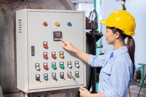 Factory engineer operate control machine pressing control panel monitor temperature of water boiler switch in factory. photo