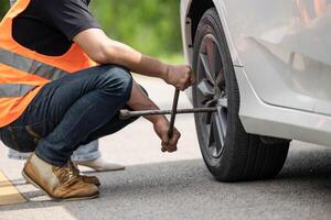 Mechanic team working road assistant help to replace flat tire service at roadside with safety reflective clothes. photo