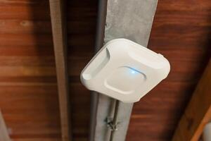 Wireless router for internet local network at ceiling. Indoor networking technology. WIFI router or Wireless Access Point setup at ceiling for Internet connection office space or cafe. photo