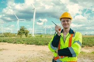 Smart Caucasian Engineer technician male worker standing at Wind Turbines working service manager at wind electricity generator farm field. photo