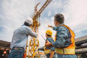 Professional construction engineer workers team working together control operating Crane tower at building project construction site. photo
