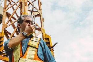 Italian worker engineer construction site control radio operation. Foreman operate crane tower working order by walkie talkie. photo