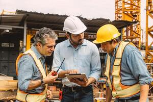 Professional construction engineer workers team working cooperate together consulting looking at tablet screen at project building construction site. photo