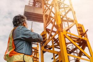 Construction engineer worker construction site radio control operation. Foreman operate tower crane working order by walkie talkie. photo