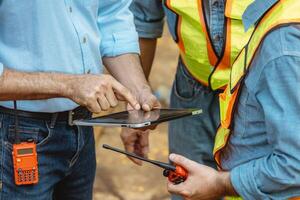 Professional construction engineer workers team working cooperate together consulting looking at tablet screen at project building construction site. photo
