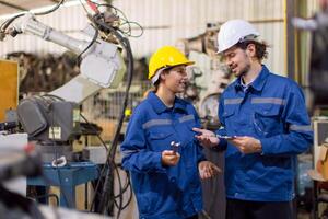 Happy engineer worker team service replace broken part of automatic industry robotic welding arm. Mechanic team repair maintenance robot machine in workshop. photo
