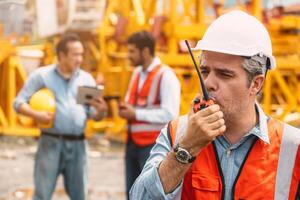 Italian worker engineer construction site control radio operation. Foreman operate crane tower working order by walkie talkie. photo
