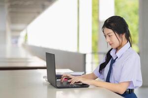 school student using laptop computer typing prompt do homework using AI technology learning education in school concept. photo