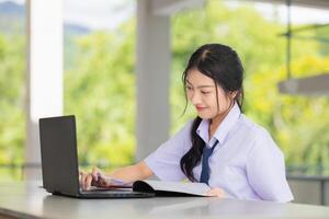 happy school uniform teen girl using laptop computer to do homework learning education in school campus, self education technology concept. photo