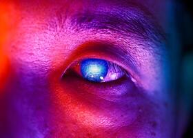 closeup chinese man colorful light digital computer circuit board pattern in the eye for future vision people with modern technology photo