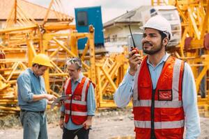 Happy Indian worker engineer construction site control radio operation. Foreman operate crane tower working order by walkie talkie. photo