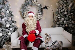 Papa Noel claus malabares con un regalo caja en Navidad decorado vivo habitación foto