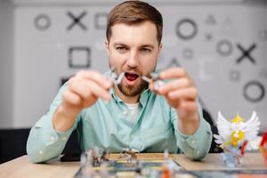 Man with board game piece while practicing strategy in home alone. A man plays a board game with cards and figures, expressing different emotions photo