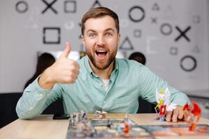 Man with board game piece while practicing strategy in home alone. A man plays a board game with cards and figures, expressing different emotions photo