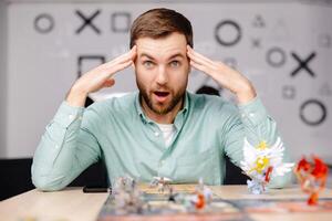Man with board game piece while practicing strategy in home alone. A man plays a board game with cards and figures, expressing different emotions photo