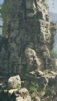 A rugged landscape with trees and boulders in the foreground, captured in China video