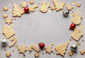 Christmas gingerbread cookies and ornaments creating festive frame on grey background photo