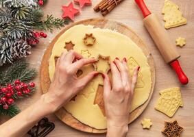 Woman using snowflake cookie cutters, baking christmas cookies photo