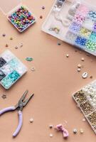 Crafting with colorful beads on a flat workspace with tools and containers in bright daylight photo