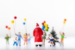 Miniature Santa Claus holding a gift surrounded by children and colorful balloons photo