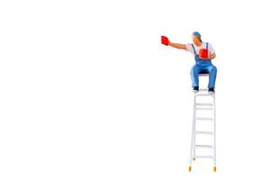 A miniature figurine of a painter seated on a ladder, holding a paint can and brush.isolate on white back ground with clipping path photo
