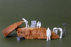 Miniature figurines dressed as forensic investigators examining bread slices with equipment photo
