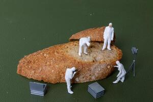 Miniature figurines dressed as forensic investigators examining bread slices with equipment photo