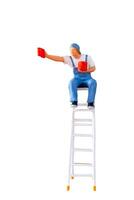 A miniature figurine of a painter seated on a ladder, holding a paint can and brush.isolate on white back ground with clipping path photo