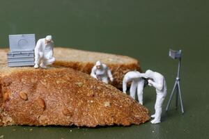 Miniature figurines dressed as forensic investigators examining bread slices with equipment photo