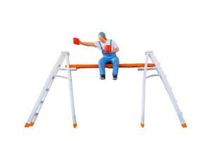 A miniature figurine of a painter seated on a ladder, holding a paint can and brush.isolate on white back ground with clipping path photo