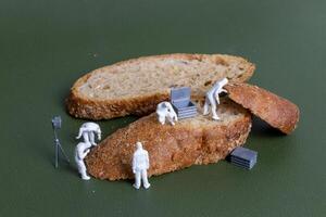 Miniature figurines dressed as forensic investigators examining bread slices with equipment photo