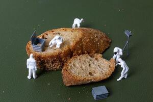 Miniature figurines dressed as forensic investigators examining bread slices with equipment photo