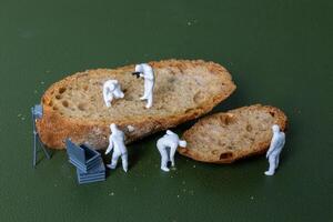 Miniature figurines dressed as forensic investigators examining bread slices with equipment photo