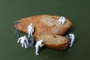 Miniature figurines dressed as forensic investigators examining bread slices with equipment photo
