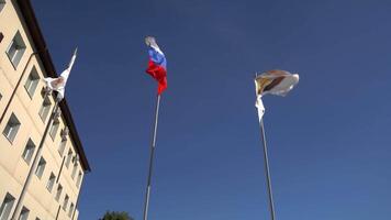 Russia, Moscow - July 15, 2024. Colorful flags are prominently displayed against a clear blue sky, symbolizing pride and unity. Stock Clip video