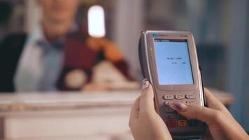 Attach the card to the terminal to print the receipt. The terminal issues a receipt. Cashier cashier makes payment for purchase by customer in sales department. video