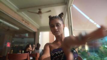 A Young Woman is Posing Playfully with Her Hands Raised High While Enjoying Time in a Cafe video