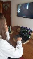 A dedicated individual is utilizing their laptop and mobile devices to monitor stock market trends video