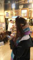 A woman browses a local art shop filled with antiques and art while using her smartphone video