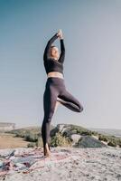 Woman Practicing Yoga in Tree Pose on a Mountaintop photo