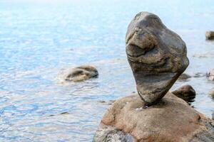 A large lone stone balances. Beautiful natural stone on the rocky shore of the lake. photo