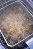 Boiling oil in a deep fryer is bubbling vigorously, indicating a high temperature suitable for frying food. photo