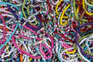 A variety of colorful beaded necklaces and bracelets laid out on a surface. Some beads are round and smooth, while others are irregularly shaped. photo