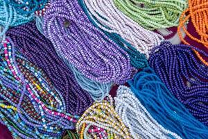 A variety of colorful beaded necklaces and bracelets laid out on a surface. Some beads are round and smooth, while others are irregularly shaped. photo
