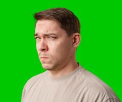 A man stands with arms crossed and a thoughtful expression in front of a green screen photo
